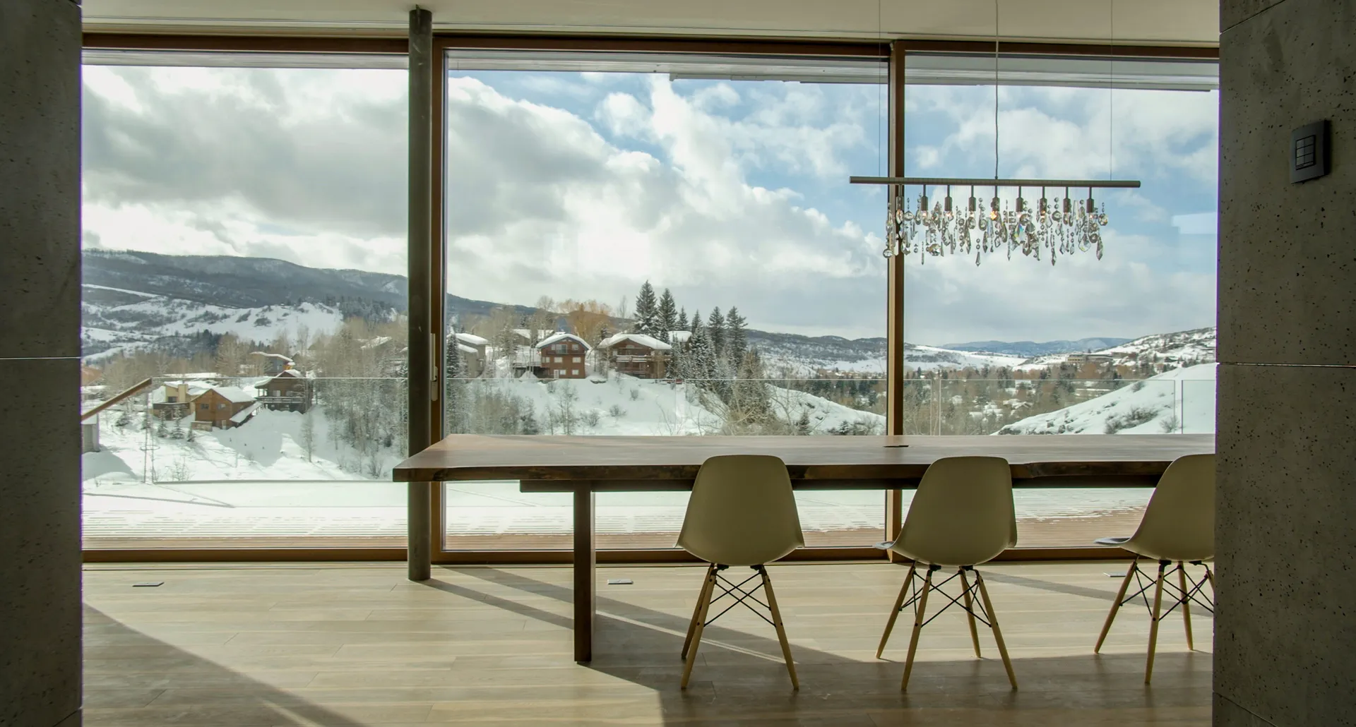 A mountain dining room with a snowy ski-town view through Zola windows