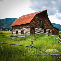 A red-roofed wooden barn in a meadow outside Steamboat Springs, Colorado